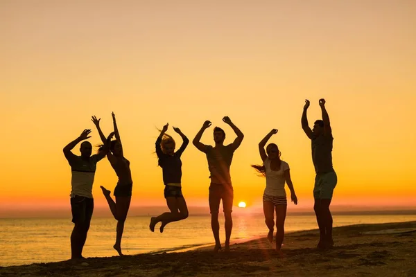 Vrienden springen op strand — Stockfoto