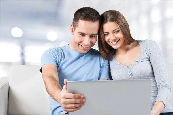 Smiling couple with laptop on sofa — Stock Photo, Image