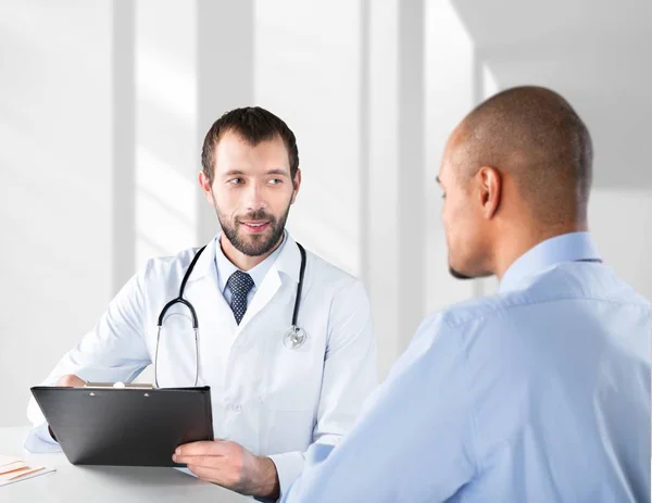 Doktor s úsměvem s pacient mužského pohlaví — Stock fotografie