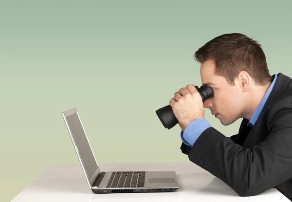 Geschäftsmann mit Fernglas vor Laptop — Stockfoto