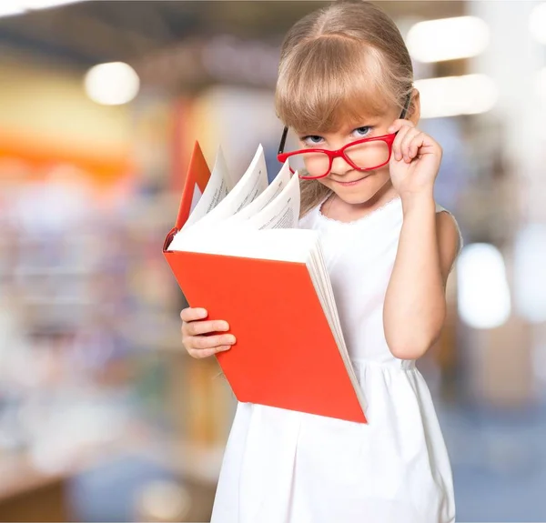 Mädchen mit Brille liest großes Buch — Stockfoto