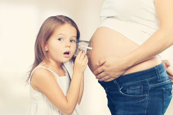Flickan att pröva moderns gravid mage — Stockfoto