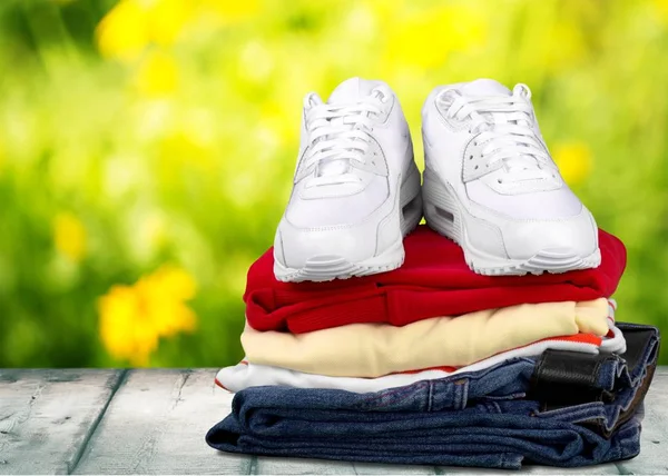 Stapel kleding met witte sneakers — Stockfoto