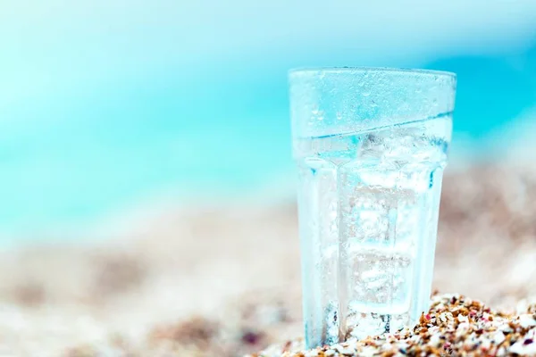 Glas water op strand zand — Stockfoto