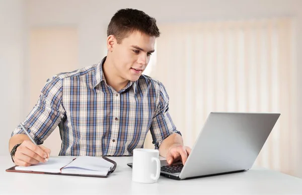 Jovem feliz trabalha em seu laptop — Fotografia de Stock