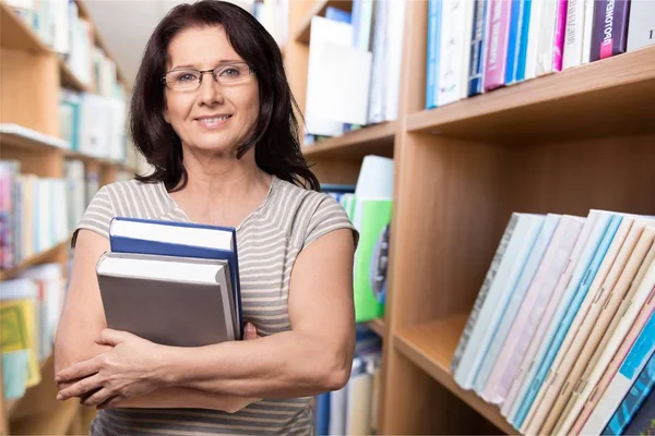 Mujer en gafas sosteniendo libros — Foto de Stock