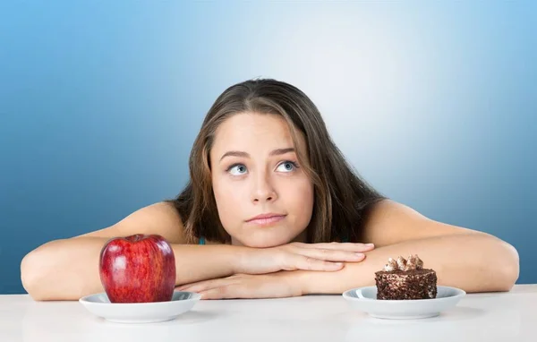 Frau trifft Wahl zwischen Apfel und Kuchen — Stockfoto