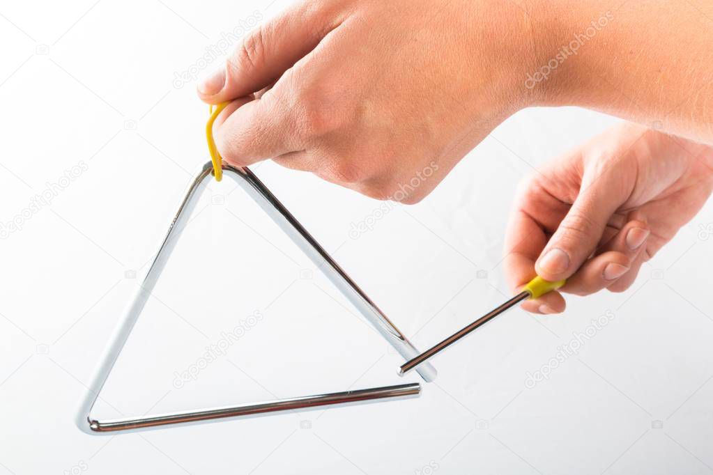 Metal triangle in hand on white background, music instrument