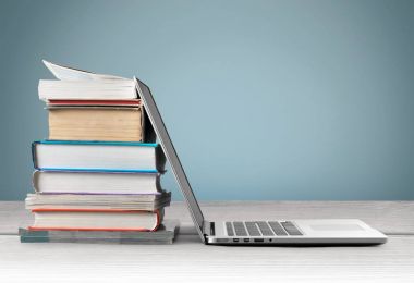 Dizüstü bilgisayar ile kitap yığını