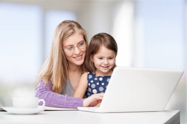 Anne ve kızı dizüstü bilgisayar kullanıyor.