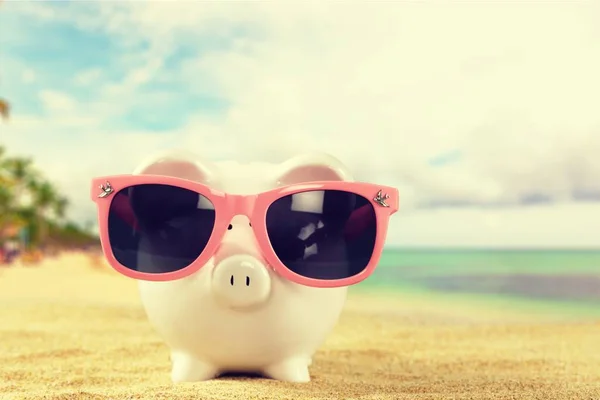 Piggy bank with sunglasses on the beach — Stock Photo, Image