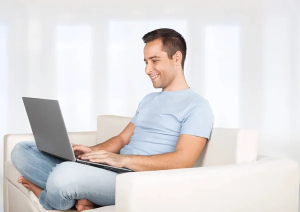 Homem relaxante no sofá com um laptop — Fotografia de Stock