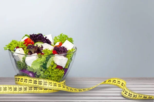 Fresh salad and measuring tape — Stock Photo, Image