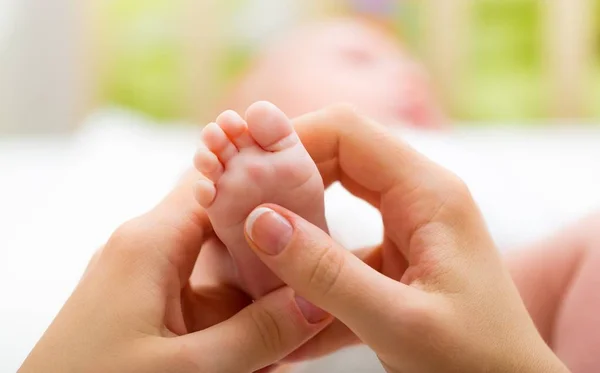 Pied de bébé dans les mains de la mère — Photo