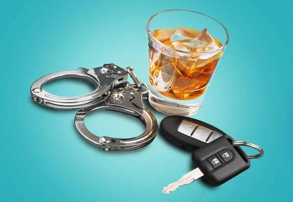 Виски с ключами от машины и наручниками — стоковое фото