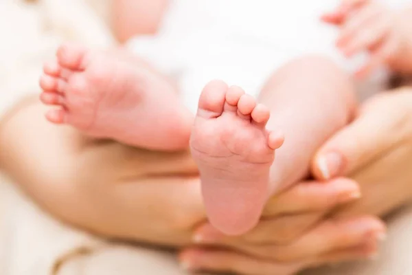 Детские ножки в материнской руке — стоковое фото