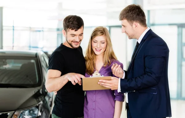 Happy couple with car dealer — Stock Photo, Image