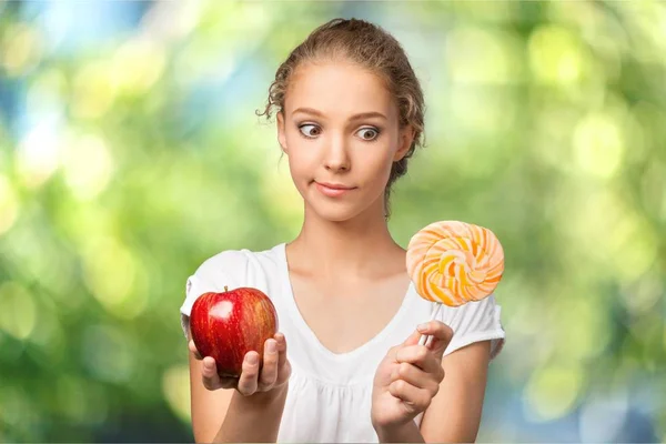 Woman holding apple and candy — Stock Photo, Image