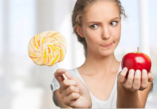 Mujer elegir entre manzana y piruleta — Foto de Stock