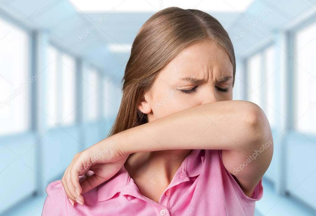 ill woman sneezing in arm