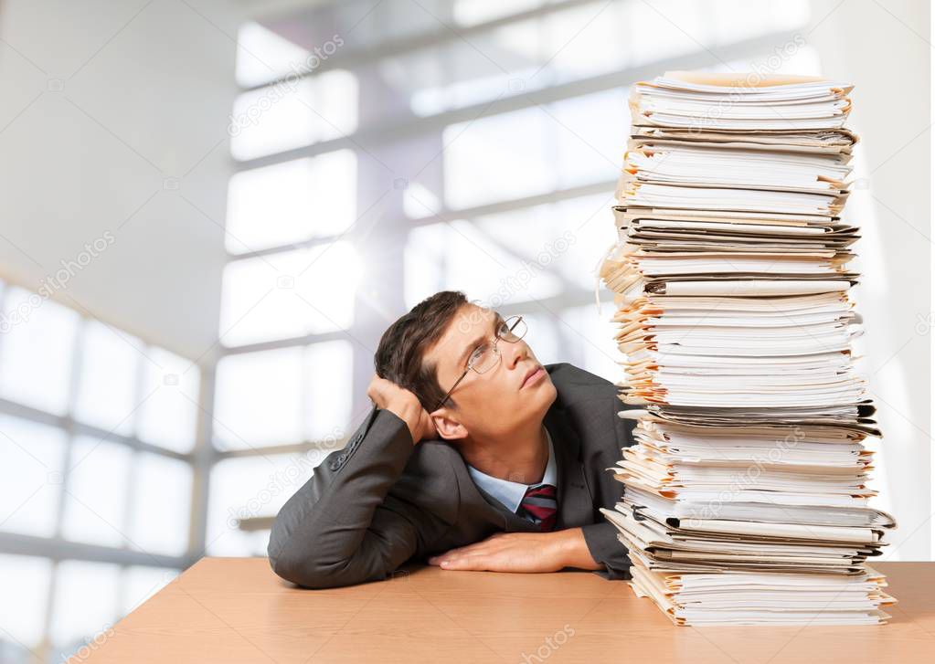 man near heap of papers 