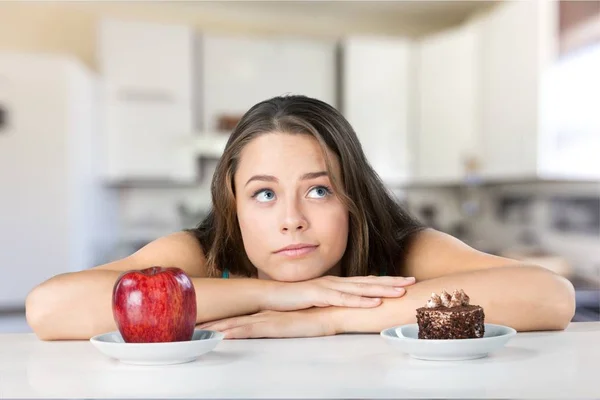 Femme fait le choix entre pomme et gâteau — Photo
