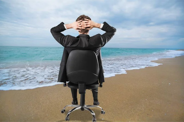 Biznesmen siedzi na krześle, nad morzem — Zdjęcie stockowe