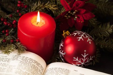 İncil'de büyük bir kırmızı mum ve Noel süsleri