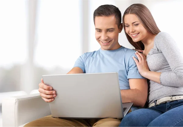 Casal sorrindo com laptop no sofá — Fotografia de Stock