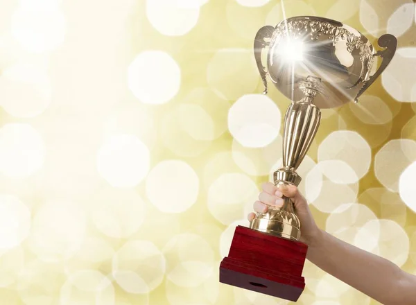 Mão segurando troféu dourado — Fotografia de Stock