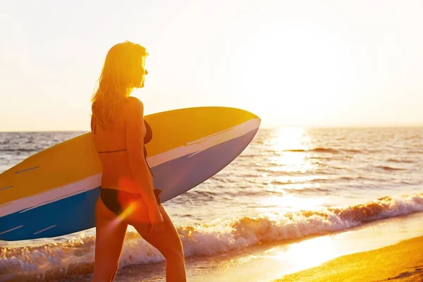 Mujer con tabla de surf en la playa —  Fotos de Stock