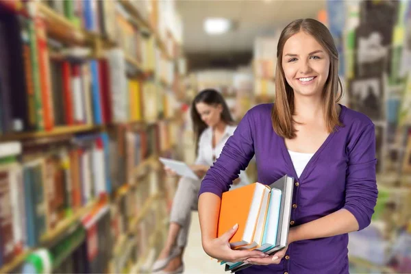 Jonge vrouwelijke student met stapel boeken — Stockfoto