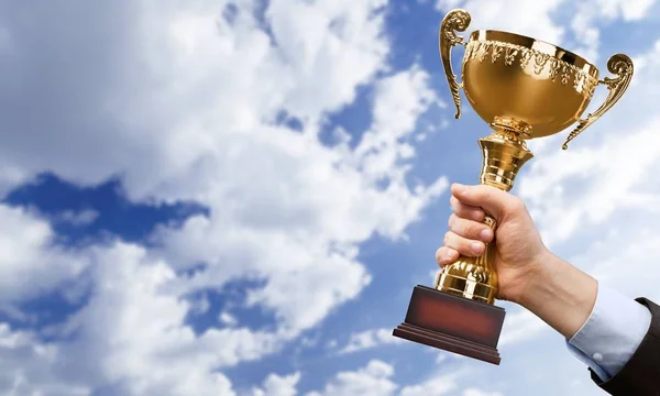 Mão segurando troféu dourado — Fotografia de Stock