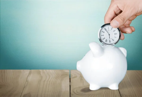 Hand depositing  clock  in piggy bank — Stock Photo, Image