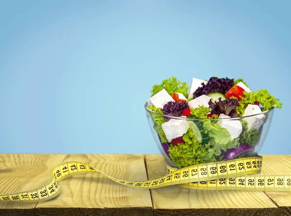 Fresh green salad and measuring tape — Stock Photo, Image