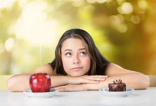Frau trifft Wahl zwischen Apfel und Kuchen — Stockfoto