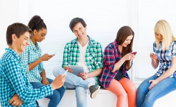 group of happy students using smartphones