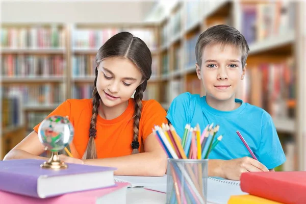 Niños sentados junto a la mesa durante la lección — Foto de Stock