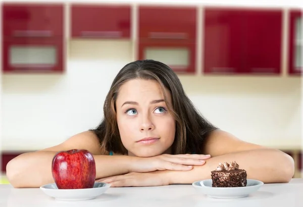 Frau trifft Wahl zwischen Apfel und Kuchen — Stockfoto