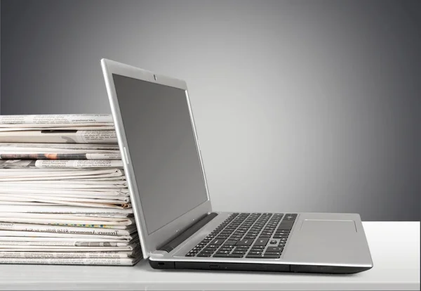 Stapel kranten met laptop — Stockfoto