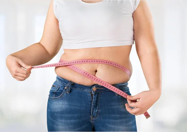 Fet kvinna som mäter sin mage — Stockfoto