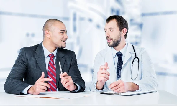 Doktor s úsměvem s pacient mužského pohlaví — Stock fotografie