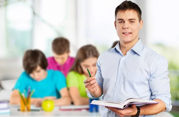 Junger männlicher Lehrer steht mit Buch — Stockfoto