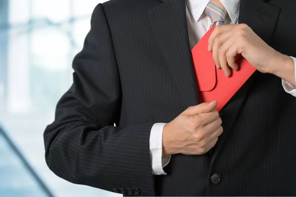 Üzletember elrejtése piros borítékot — Stock Fotó