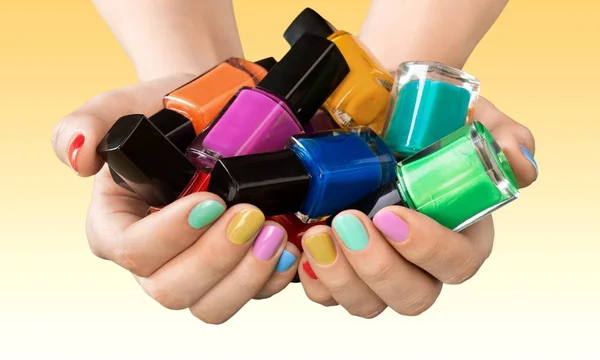 Ruce držící barevné laky na nehty — Stock fotografie