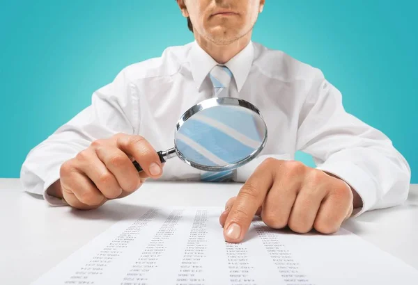 Businessman looking in magnifying glass — Stock Photo, Image