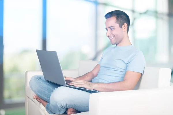 Homem relaxante no sofá com um laptop — Fotografia de Stock