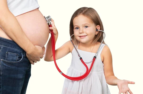 Girl examining her pregnant mother's belly — Stock Photo, Image