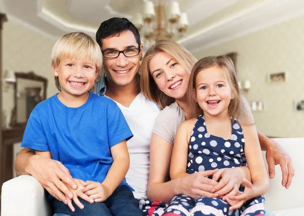 Usmívající se rodina sedí doma — Stock fotografie