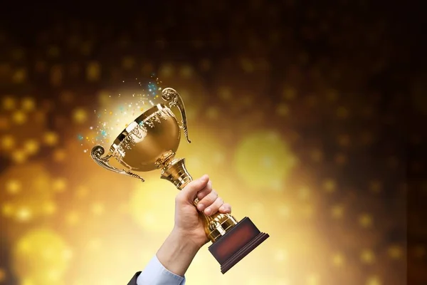 Mão segurando troféu dourado — Fotografia de Stock